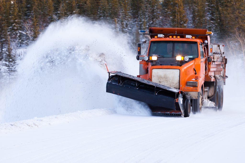 Snow plow operating on a road filled with snow and ice that uses Cypress VUE